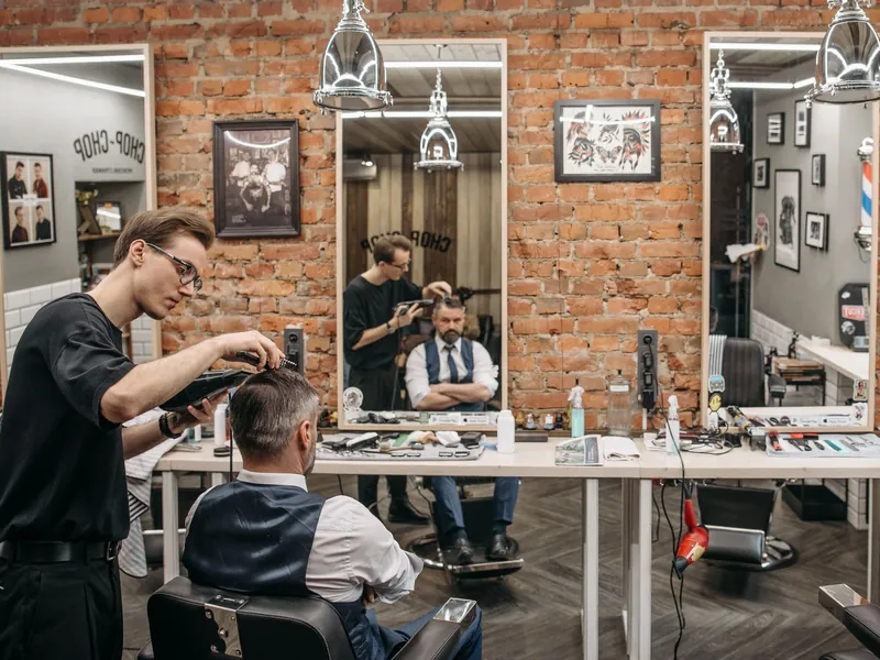 A barber cutting a client&rsquo;s hair in a barbershop.